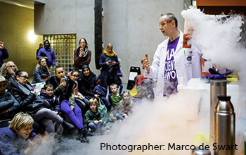 Mad scientist surrounded by smoke holding beaker with smoke pouring out. 