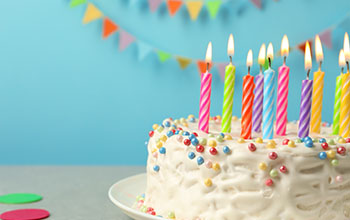 Delicious birthday cake with burning candles on table